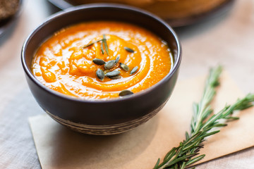 Pumpkin soup decorated on a table with a sprig of rosemary