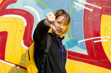 Teenager shows dislike sign on bright background