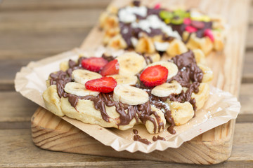 gofre con chocolate y fruta en plato de cartón reciclado y tabla de madera