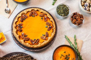 Pumpkin pie decorated with pecans on a served table for an autumn party food
