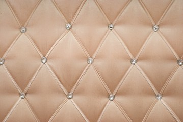 Fototapeta na wymiar Light beige textile background, retro Chesterfield style checkered soft tufted fabric furniture diamond pattern decoration with buttons, close up