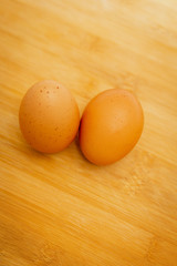 Two brown eggs isolated In a white cup on Wood background