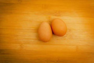 Two brown eggs isolated In a white cup on Wood background