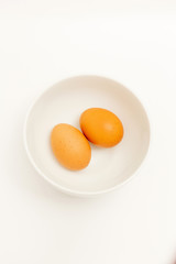 Two brown eggs isolated In a white cup on Wood background