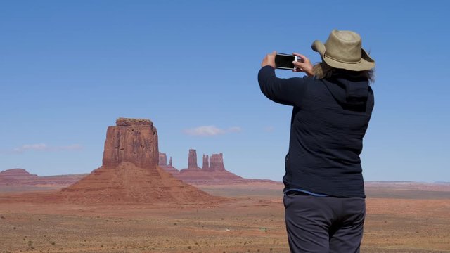 Woman At Top Of Viewpoint Valley Of Monuments Takes A Photo On A Smartphone
