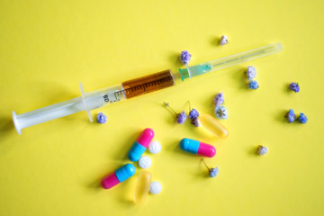 Assorted medical drugs and syringe on yellow background, with copy space. Pharmaceutical medicine pills concept. Coronavirus COVID-2019 vaccine and protection. Health care and medical insurance.