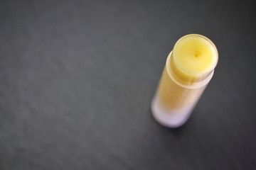 Extreme closeup of beeswax homemade lip balm on dark gray background. Macro with shallow DOF, top view.