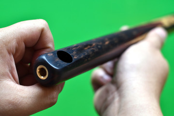 Fototapeta premium Close-up view, Snooker cue stick in holding hand with green background.