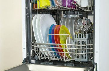 colorful Dishware inside built-in dishwasher. Dishwashing machine rack