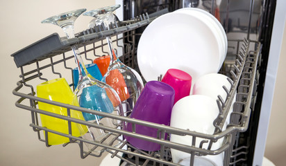 colorful Dishware inside built-in dishwasher. Dishwashing machine rack