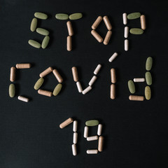 STOP COVID-19 sign written using vitamins and drugs. Coronavirus 19. Dark background. Lay flat....
