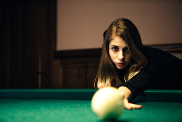 Skinny girl playing billiards 