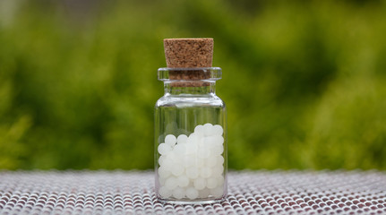 Homeopathy, globules in a glass bottle, nature background