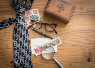 Masculine background of pine wood with leather box, black and silver neck tie, old stamps and other men's accessories for a fathers day holiday look