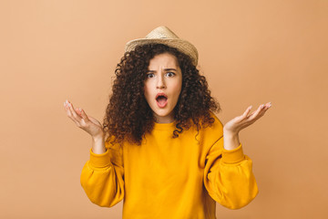 Portrait with copy space for advertisement of shocked afraid woman looking with eyes at empty place having wide open mouth eyes gesturing palms isolated on beige background.