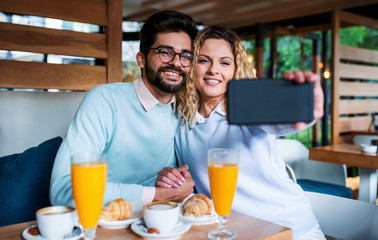 Young couple sitting in a cafe, having breakfast. Love, dating, food, lifestyle concept