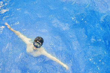 Man in an underwater mask emerges from the water. diving in the ocean on vacation.