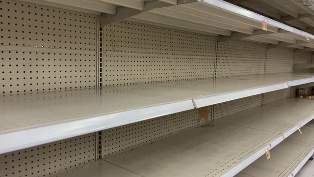 Empty grocery store shelves due to panic buying during Covid-19 pandemic. Hoarders purchasing canned goods and toilet paper in fear of being quarantined from coronavirus leave a supermarket shelf bare