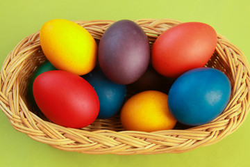 Obraz na płótnie Canvas Easter eggs colors in basket green background