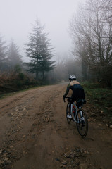 Fototapeta na wymiar Female cyclist rides fast up a gravel road