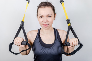 Young attractive woman training with trx fitness straps