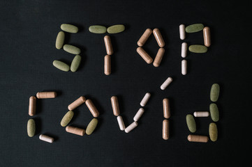 STOP COVID-19 sign written using different color vitamins and drugs. Coronavirus 19. Dark background. Lay flat. Smooth image with shallow depth of field.