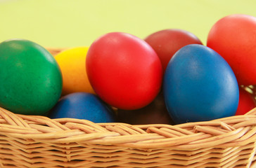 Fototapeta na wymiar Easter eggs colors in basket green background