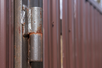 Old rusty loop of a metal fence (gate) of brown color. Fence made of brown metal fencing bolted vertically.