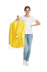 Young woman holding hanger with jacket in plastic bag on white background. Dry-cleaning service