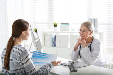 Doctor consulting patient at desk in clinic