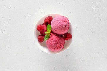 Raspberry ice cream scoop with fresh raspberries in bowl