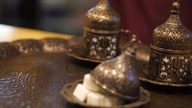 Coffee ceremony. man puts a copper cezve on a tray with oriental beautiful cups