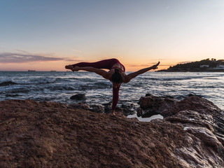 Young woman practicing the yoga pose Fire hydrant in front of the sea