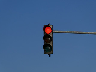 Red color on the traffic light with blue sky in background