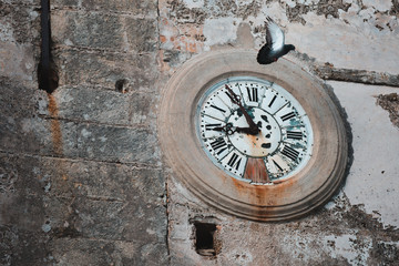 Time Flies: An Antique Circle Street Clock on an Old Wall with Pigeon on Vejer de la Frontera, Cadiz, Spain