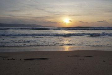 Fototapeta na wymiar Golden dawn at sea, waves running onto the sand