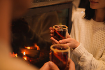 Couple with tasty mulled wine near fireplace indoors, closeup