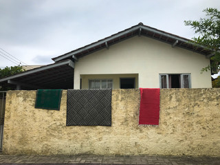 Rugs hang on the fence. The White House behind a simple fence. country house