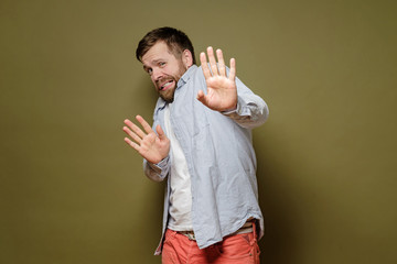 Frightened man is afraid of getting the virus, he makes a stop gesture with hands and looks with...