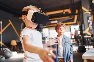 Child in virtual reality eyewear and in casual clothes have fun in playroom