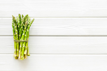 Bunch of asparagus steams on white wooden background top-down copy space
