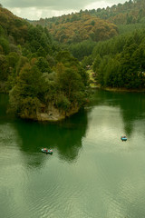 mountains and green water dam with boats in an ecological park