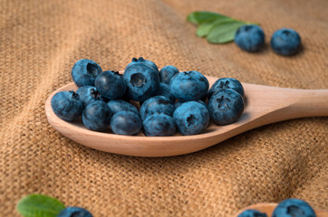Fresh blueberries lie in a wooden spoon on a natural wooden background. Eco products for human health. Healthy eating concept flat lay. Copy spase