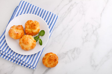 Profiteroles with custard decorated with mint on a marble background, top view