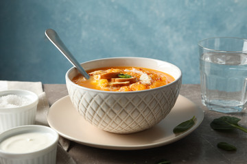 Pumpkin cream soup with croutons on grey table, close up