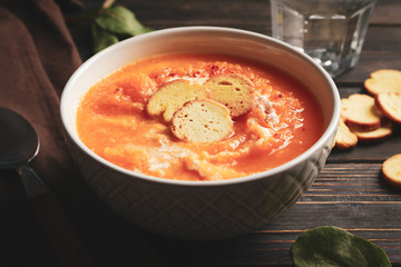 Pumpkin cream soup with croutons on wooden background, close up