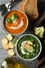Sweet potato and broccoli cream soups on wooden background, top view