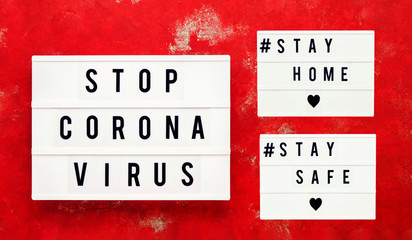 STOP CORONA VIRUS, STAY HOME and STAY SAFE written in light box on red background. Healthcare and medical concept. Top view. Quarantine concept.