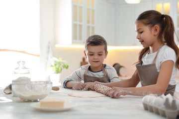 Obraz na płótnie Canvas Cute little children cooking dough together in kitchen