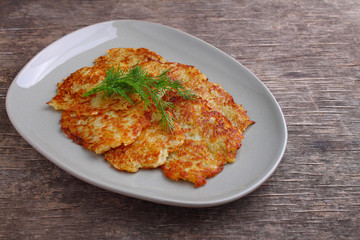 Potato pancakes in a plate decorated with dill on a rustic background